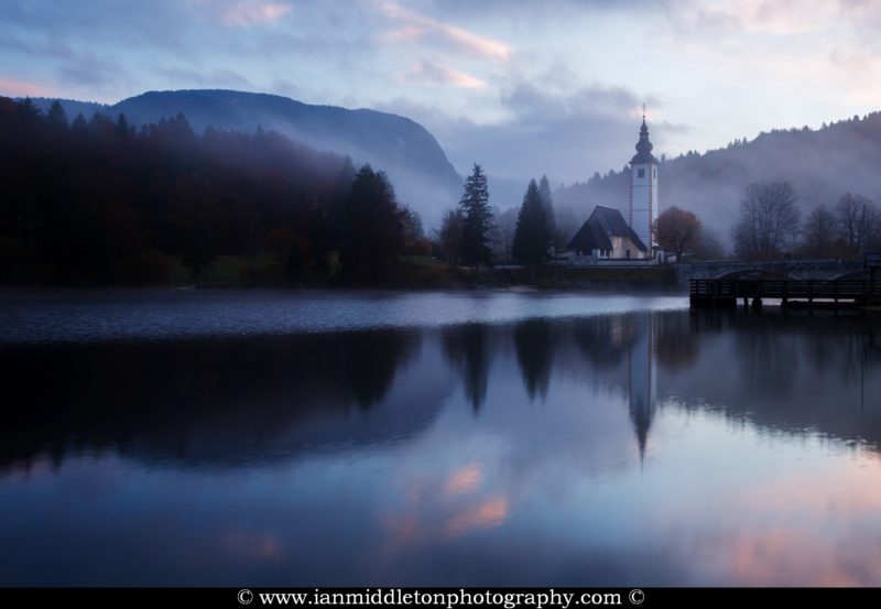 Morning mist and cloud over Lake Bohinj and the Church of Saint John at sunrise, Triglav National Park, Slovenia