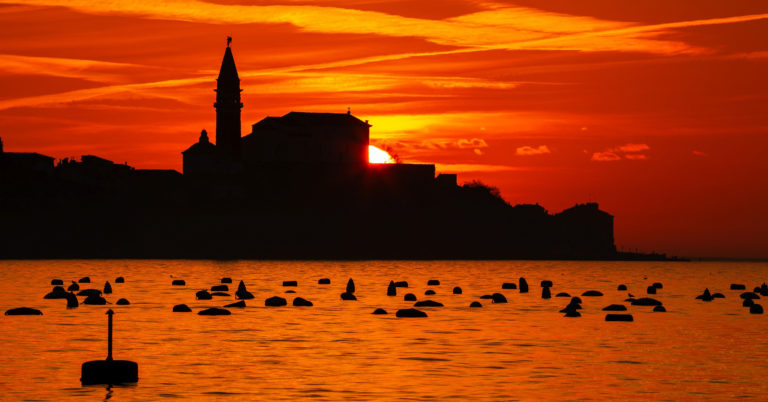 View of Saint George's Parish Church in Piran at sunset, seen from Strunjan, on the Adriatic Coast in Slovenia.