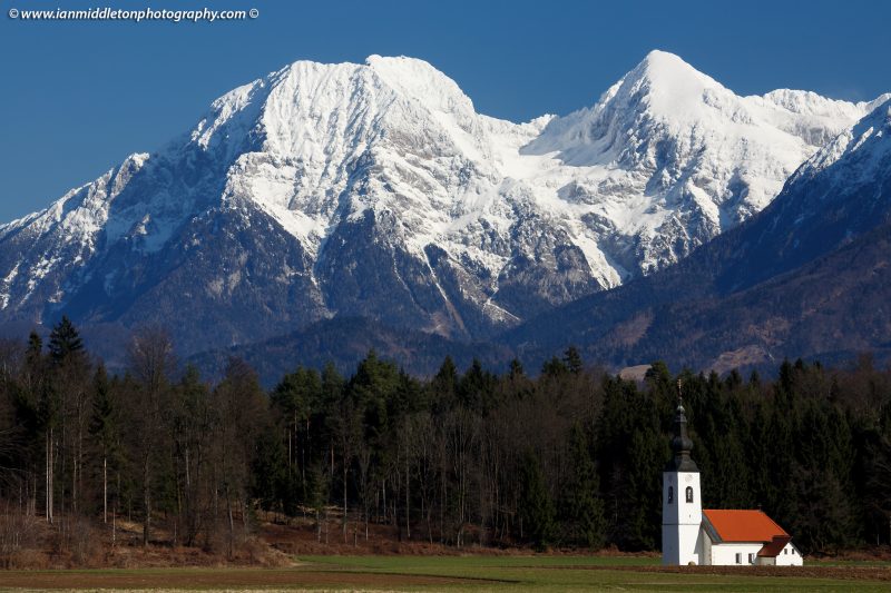 The church of Saint James in the little village of Hrase, near Medvode in Gorenjska, Slovenia, with the snowcapped Kamnik Alps behind.