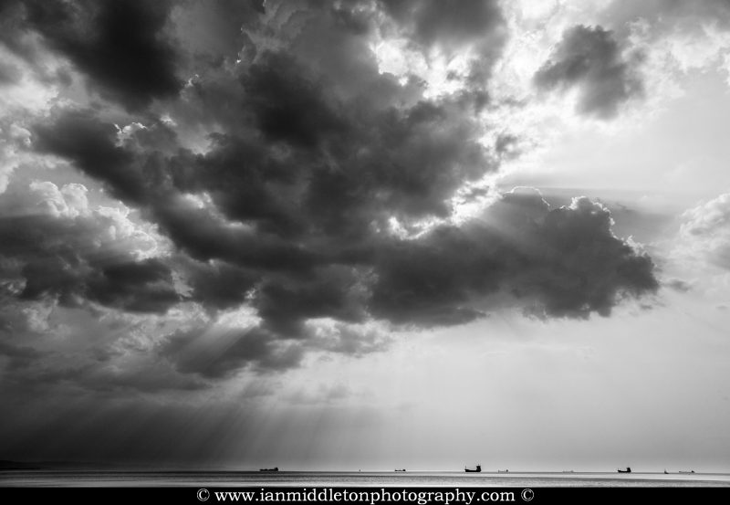 Scattered clouds produce beautiful rays of sunlight over the ships entering and leaving trieste Bay, Italy.