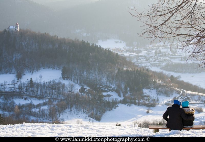 Couple sitting on a bench enjoying the evening view across to the church of Sveti Josef (Saint Joseph) from the church of Saint Anna (Sveta Ana). Sveta Ana is perched upon an exposed hill overlooking the Ljubljansko Barje (Ljubljana marsh) near the village of Preserje.