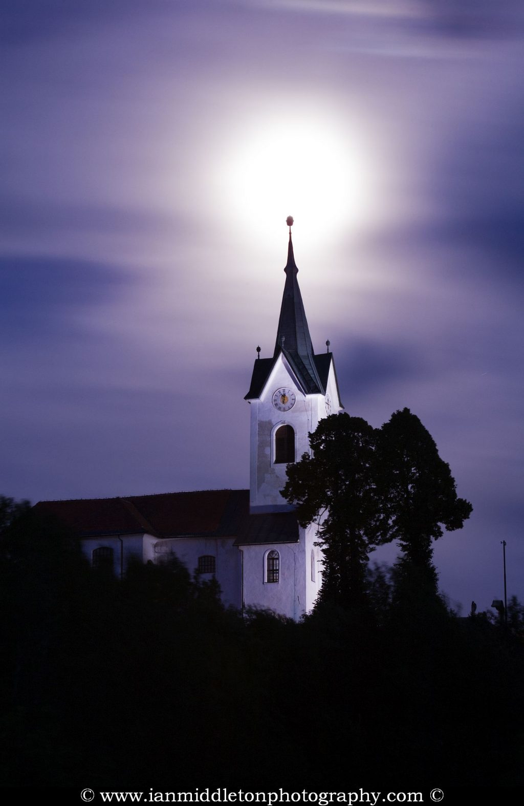 The 2013 supermoon rises over the spire of the church of Saint Marjeta (Sveta Marjeta) in Prezganje in the Jance hills to the east of Ljubljana, Slovenia. This was shot on the evening of June 22nd, the night before totality and the moon was approximately 98% full.