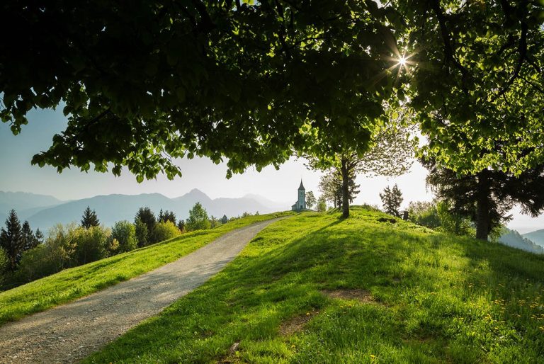 Jamnik church of Saints Primus and Felician, perched on a hill on the Jelovica Plateau with the kamnik alps and Storzic mountain in the background, Slovenia