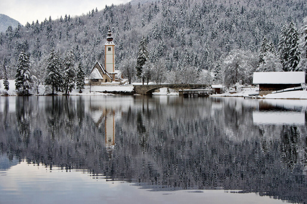 View across to the church of Saint John (Sveti Janez), Lake Bohinj in Winter, Slovenia