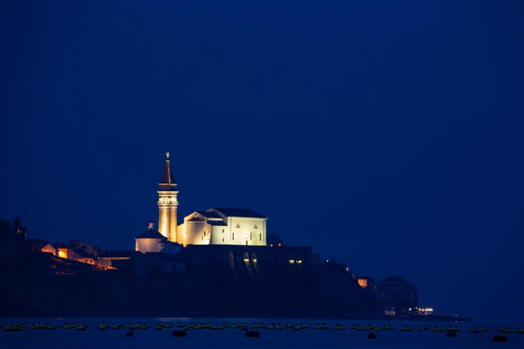 View of Saint George&#039;s Parish Church in Piran at dusk, seen from Strunjan, on the Adriatic Coast in Slovenia.