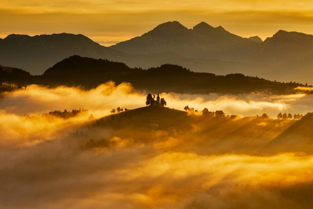 View at sunrise from Rantovše hill across to Sveti Tomaz nad Praprotnim (church of Saint Thomas) and the Kamnik Alps, Slovenia.