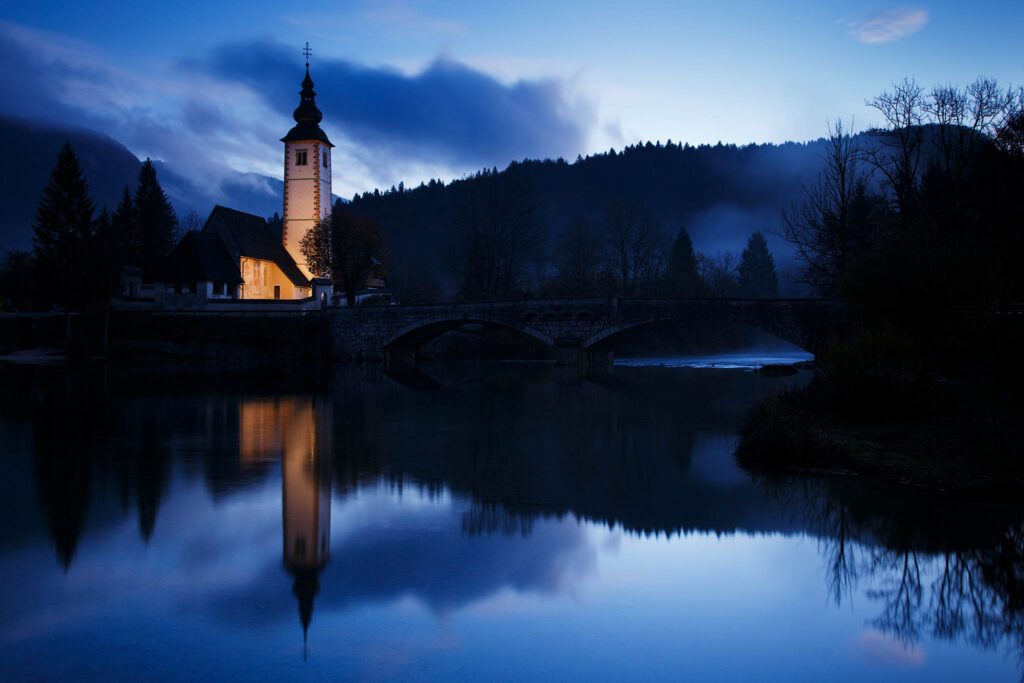 Dawn light over Lake Bohinj and the church of Saint John (Sveti Janez), Triglav National Park, Slovenia