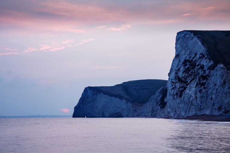 View across the cliffs to Bats Head from Durdle Door beach as the sun goes down for the evening, Dorset, England. Durdle door is one of the many stunning locations to visit on the Jurassic coast in southern England.