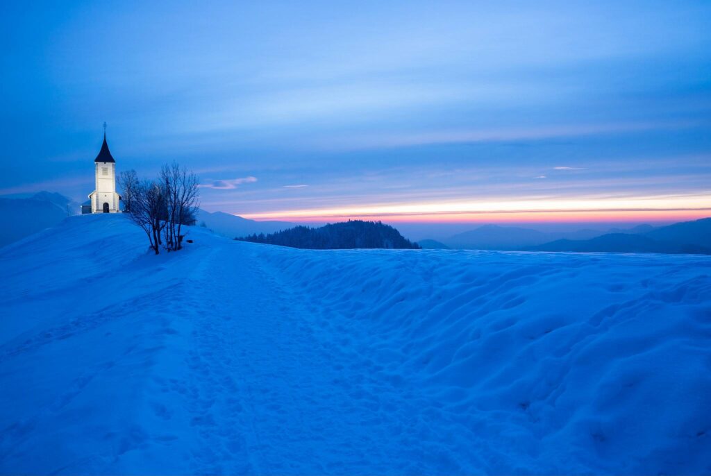 Jamnik church of Saints Primus and Felician at sunrise in winter, perched on a hill on the Jelovica Plateau, Slovenia.