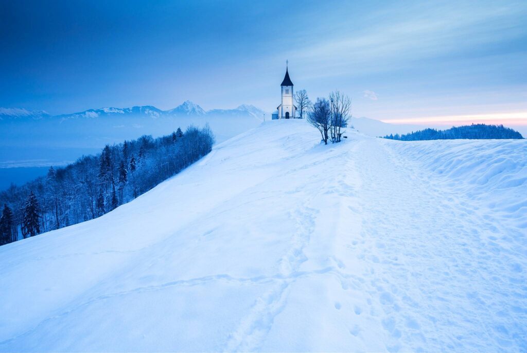 Jamnik church of Saints Primus and Felician just before sunrise in winter, perched on a hill on the Jelovica Plateau, Slovenia.