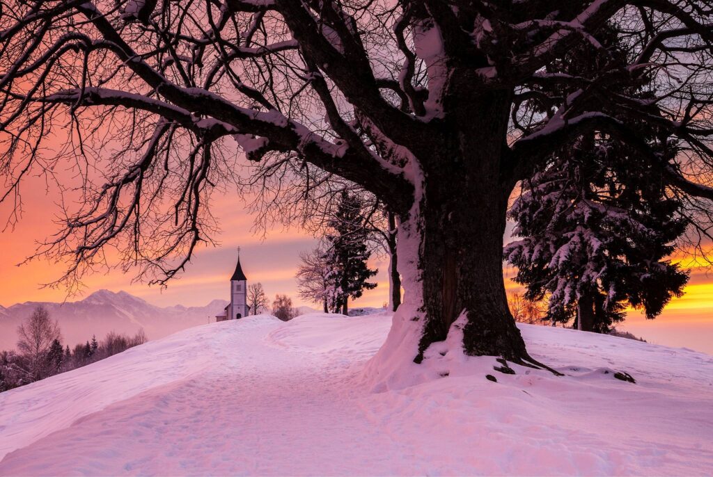 Jamnik church of Saints Primus and Felician at sunrise, perched on a hill on the Jelovica Plateau with the kamnik alps and storzic mountain in the background, Slovenia.