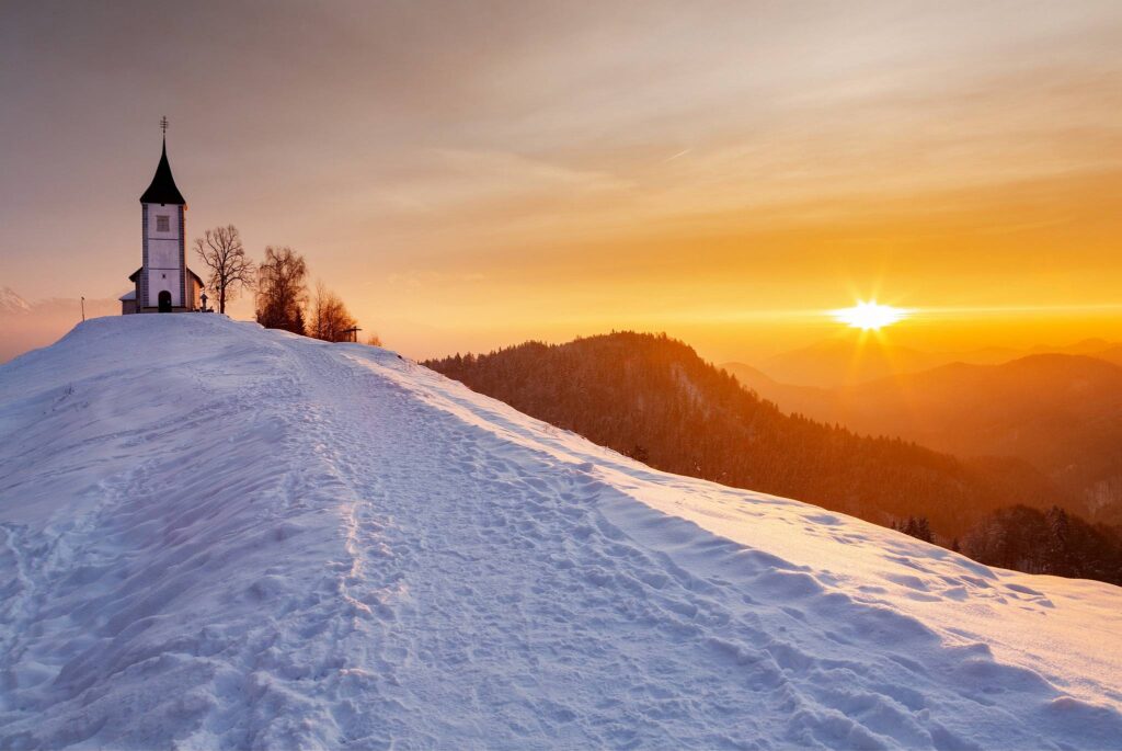 Jamnik church of Saints Primus and Felician at sunrise in winter, perched on a hill on the Jelovica Plateau, Slovenia.