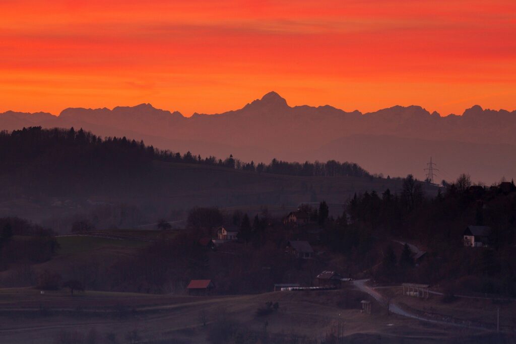 View across the village of Volavje to the Julian Alps and the highest peak, Triglav, at sunset. Volavlje is a small village in the hills east of Ljubljana, Slovenia.