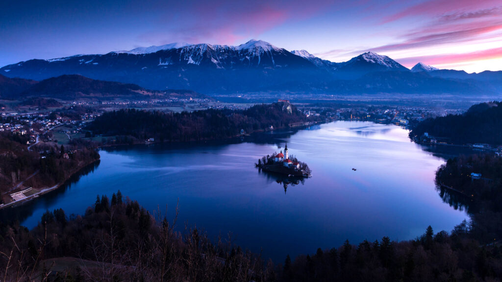 Sunrise over Lake Bled to the island church and clifftop castle from Mala Osojnica, Slovenia.