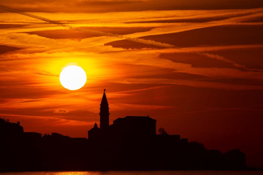 View of Saint George&#039;s Parish Church in Piran at sunset, seen from Strunjan, on the Adriatic Coast in Slovenia.