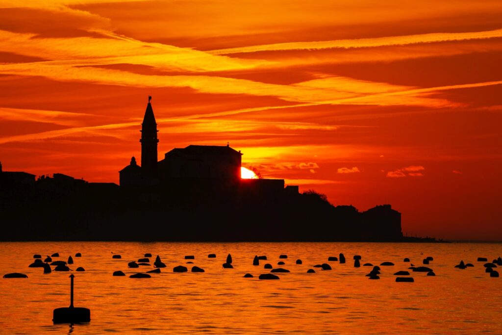 View of Saint George&#039;s Parish Church in Piran at sunset, seen from Strunjan, on the Adriatic Coast in Slovenia.