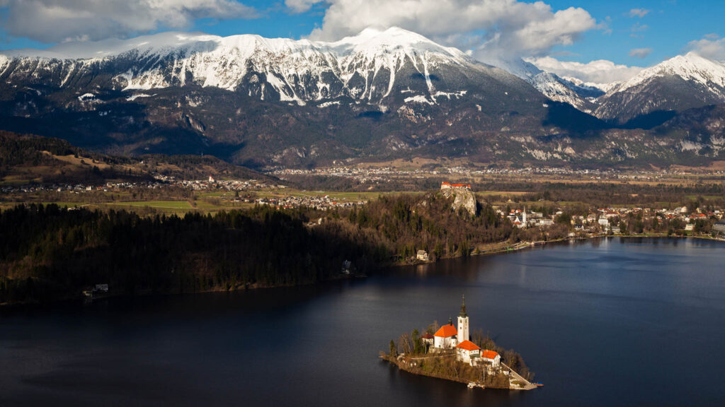 View across Lake Bled to the island church and clifftop castle from Mala Osojnica, Slovenia.