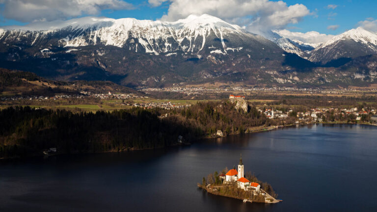 View across Lake Bled to the island church and clifftop castle from Mala Osojnica, Slovenia.