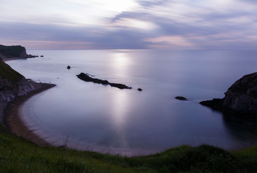 The rising moon casting beautiful moonlight over Man of War Bay, near Durdle Door, Dorset, England. Durdle door is one of the many stunning locations to visit on the Jurassic coast in southern England.