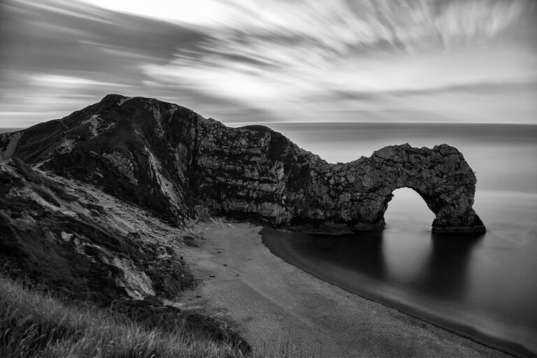 Black and white photo of Durdle Door Beach seen from the cliffs above, Dorset, England.