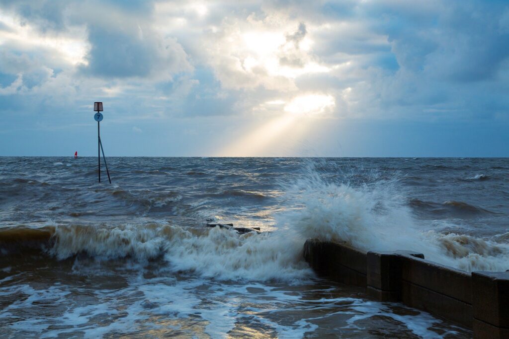 Waves crashing over groyne at Hunstanton beach at sundown, West Norfolk, England.