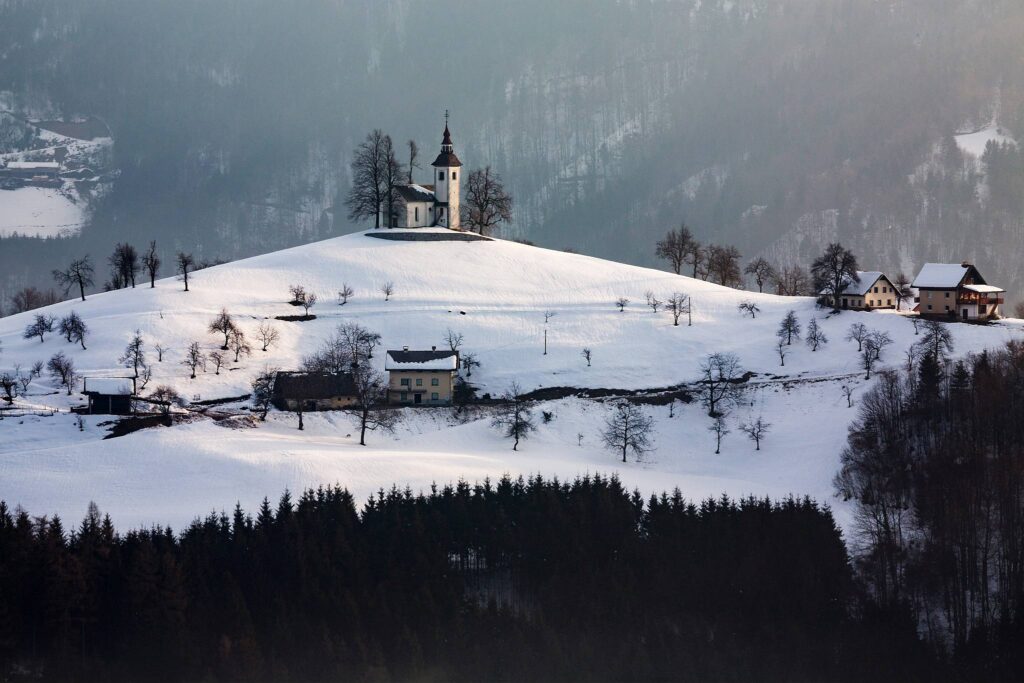 View in winter from Rantovše hill across to Sveti Tomaz nad Praprotnim (church of Saint Thomas) and the Kamnik Alps, Slovenia.