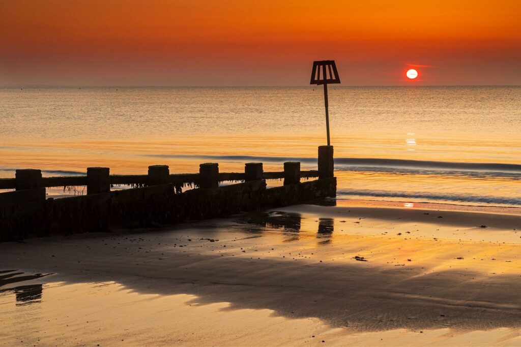 Sun rising Swanage Beach and Groyne, Dorset, England.