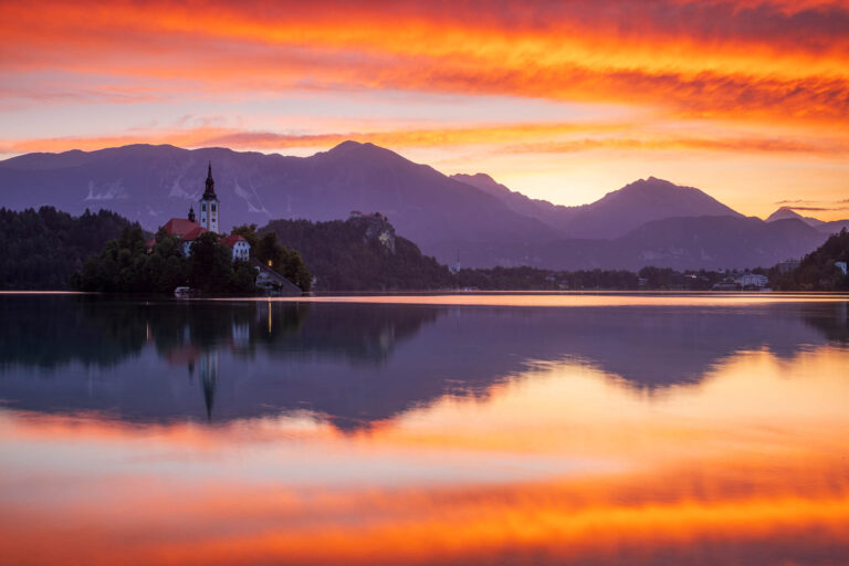 Sun rising over Lake Bled and the castle, island church of the assumption of Mary with the Karavanke mountains in the background, Slovenia.