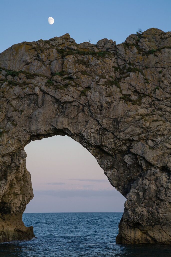 Close up of Durdle Door in the evening with the rising moon above it, Dorset, England. Durdle door is one of the many stunning locations to visit on the Jurassic coast in southern England.