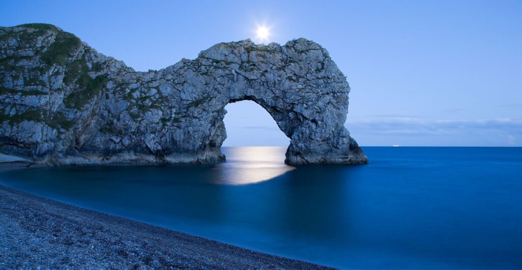 Durdle Door in the moonlight, Dorset, England. Captured late evening as the moonlight flooded through the rock&#039;s archway. Durdle door is one of the many stunning locations to visit on the Jurassic coast in southern England.