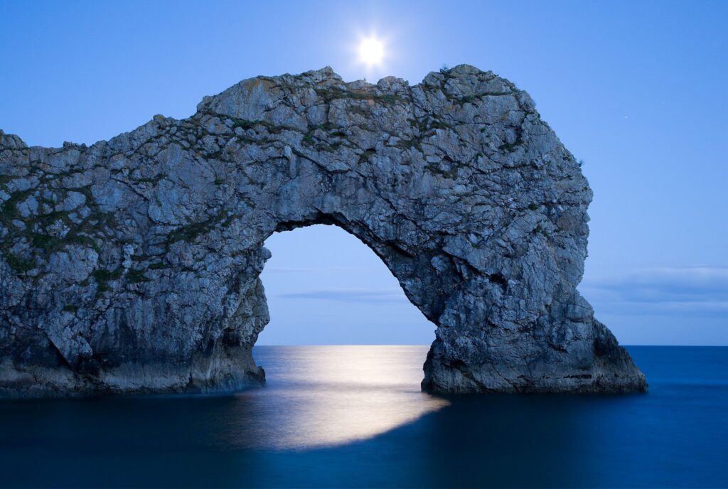 Durdle Door in the moonlight, Dorset, England. Captured late evening as the moonlight flooded through the rock&#039;s archway. Durdle door is one of the many stunning locations to visit on the Jurassic coast in southern England.