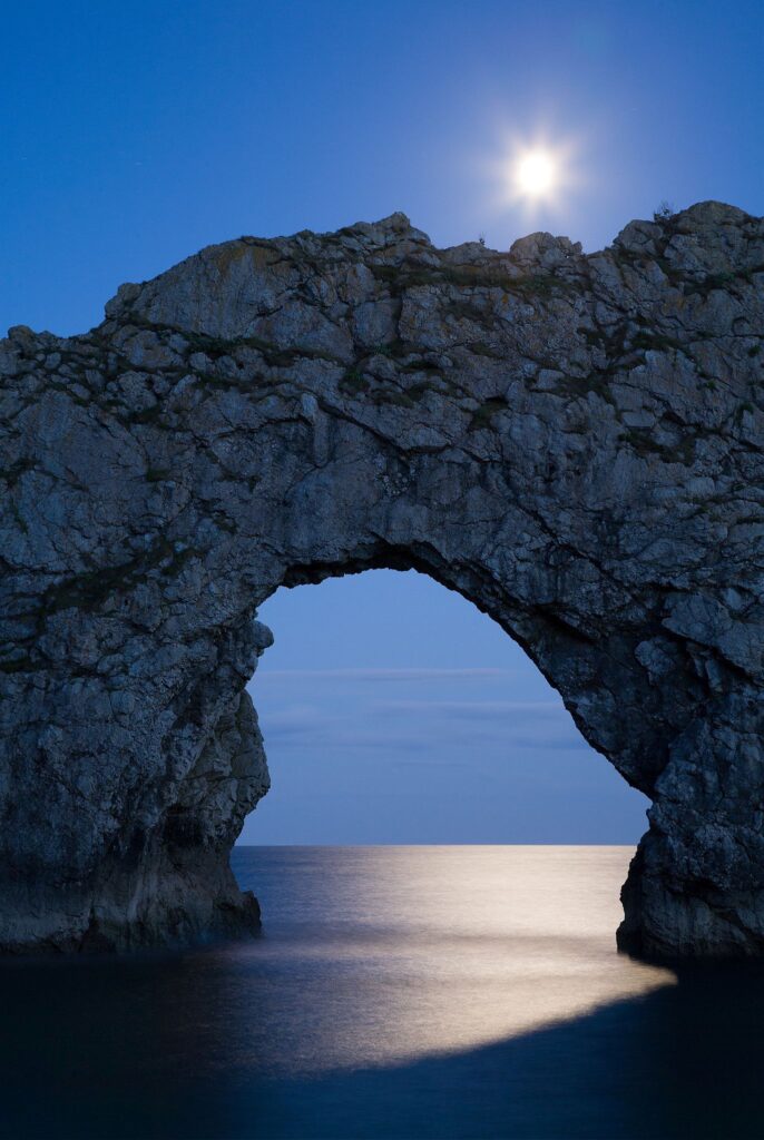 Durdle Door in the moonlight, Dorset, England. Captured late evening as the moonlight flooded through the rock&#039;s archway. Durdle door is one of the many stunning locations to visit on the Jurassic coast in southern England.