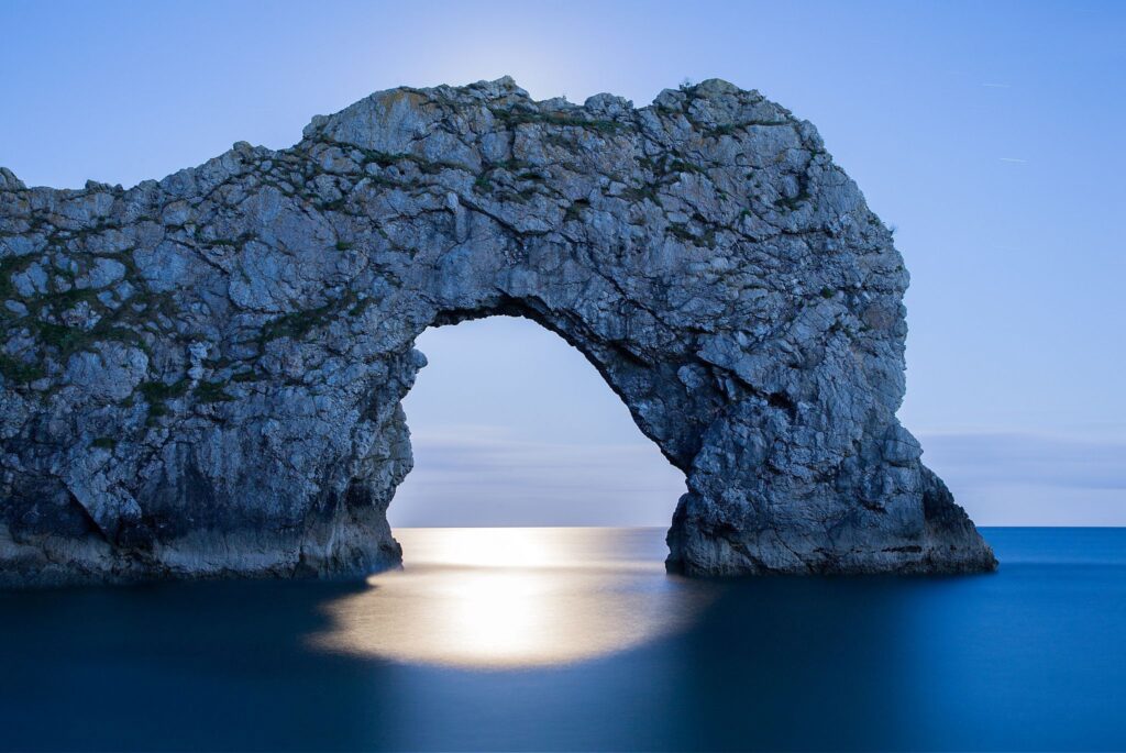 Durdle Door in the moonlight, Dorset, England. Captured late evening as the moonlight flooded through the rock&#039;s archway. Durdle door is one of the many stunning locations to visit on the Jurassic coast in southern England.