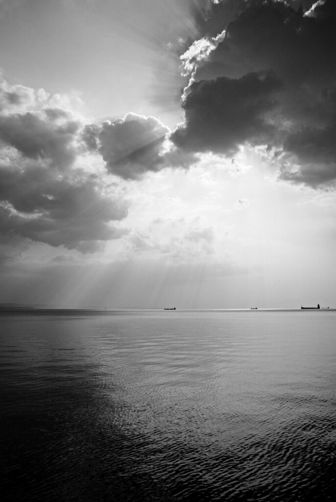 Scattered clouds produce beautiful rays of sunlight over the ships entering and leaving trieste Bay, Italy.