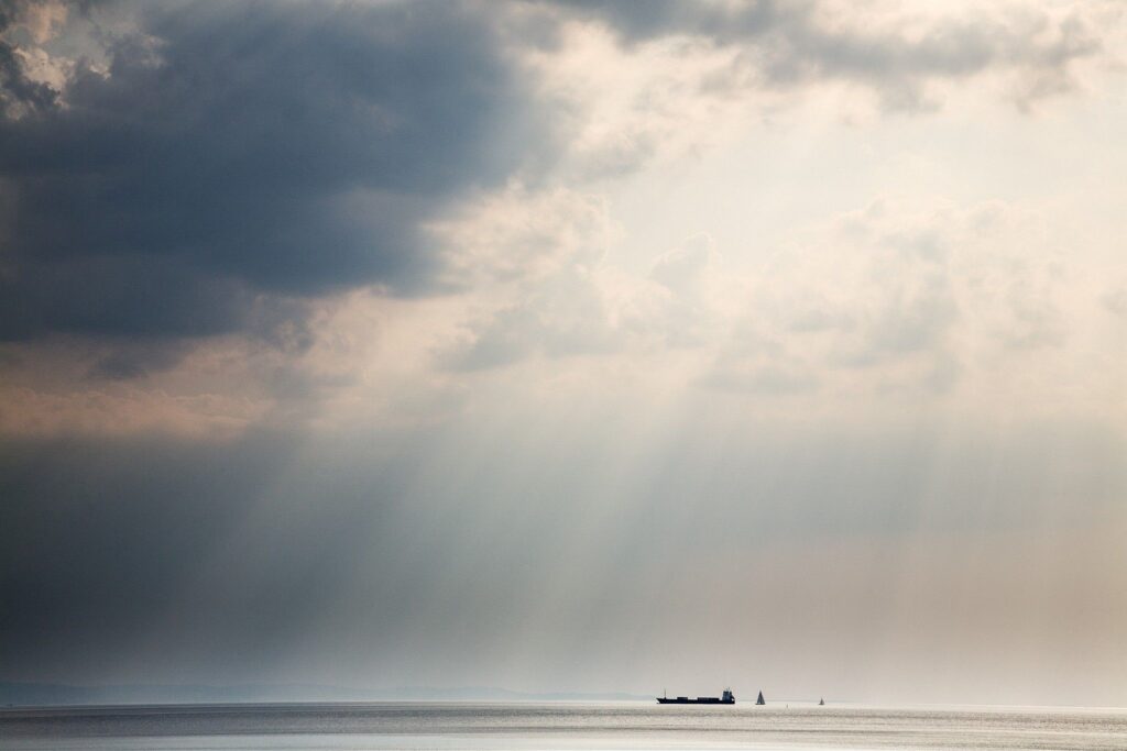 Scattered clouds produce beautiful rays of sunlight over the ships entering and leaving trieste Bay, Italy.