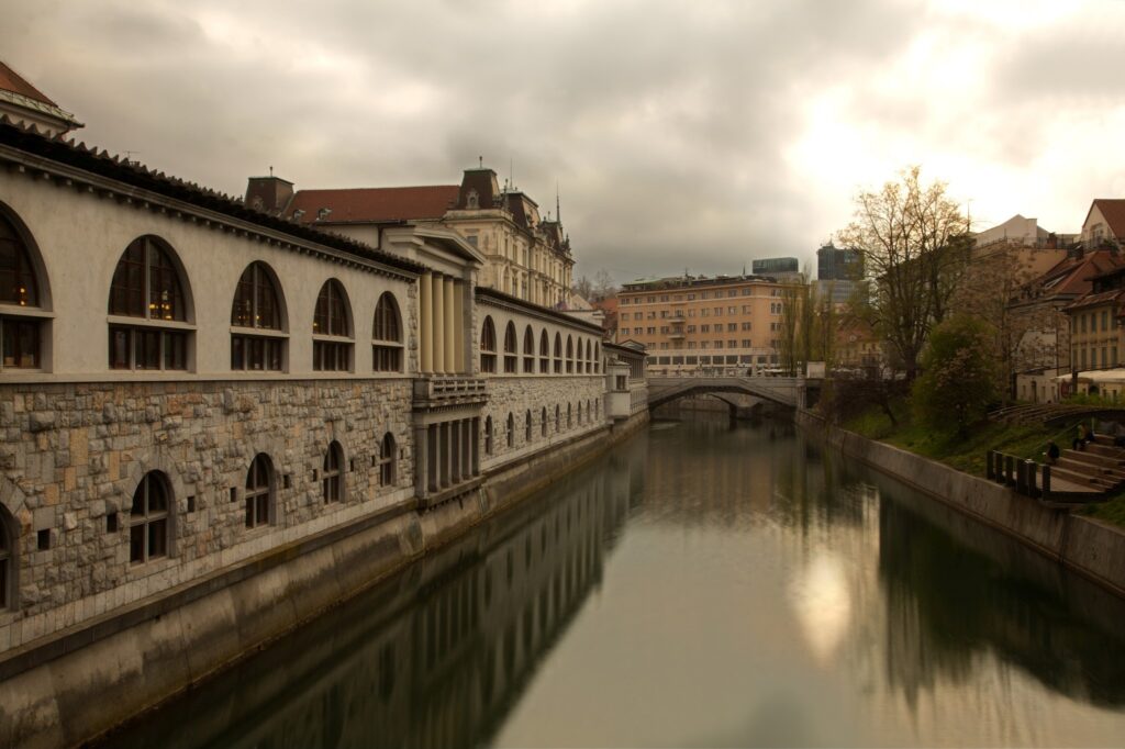 View across the Ljubljanica River that runs through the centre of Ljubljana, the capital of Slovenia. On the left you can see the Trznica (market place) and ahead is the famous Tromostovje (triple bridge), all designed by Slovenia&#039;s foremost architect, Joze Plecnik.