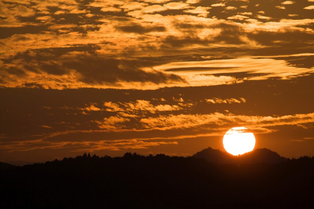 Sun setting between two mountain peaks to the west of Ljubljana, Slovenia.