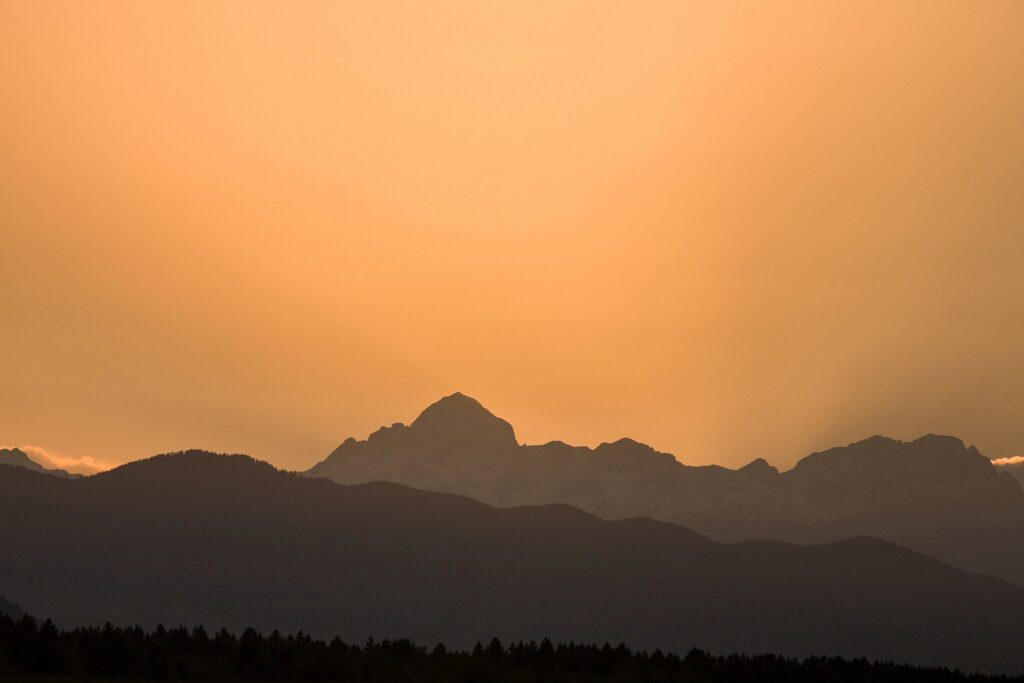 Sun setting behind the jagged peaks of the Julian Alps, Slovenia.