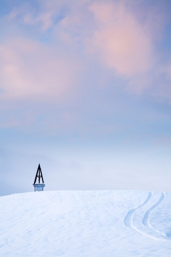 Sunset winter view across a hill in prezganje in the Jance hills to the east of Ljubljana, Slovenia. Vehicle tracks are leading up to a shrine. The shrine is to Jesus Christ, built to commemorate the first visit of Pope John Paul the second to Slovenia in 1996.