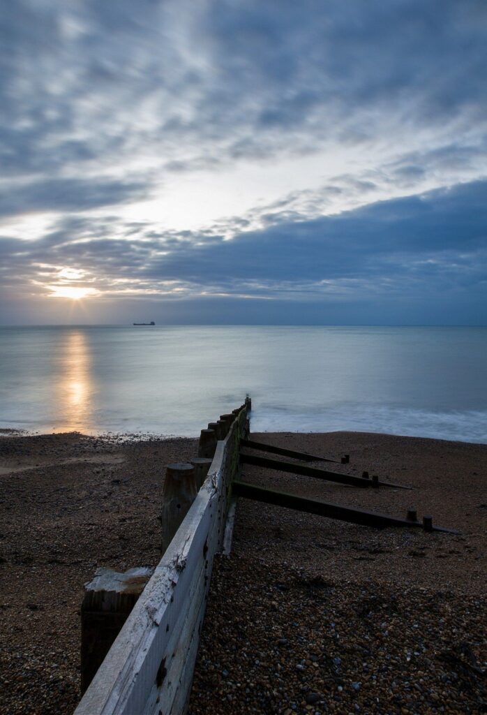 View out to sea in the morning from Kingsdown beach, near the famous White Cliffs of Dover, Kent, England. A cargo ship is anchored in the distance.