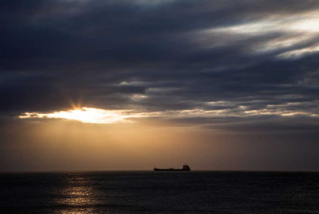 View out to sea in the morning from Kingsdown beach, near the famous White Cliffs of Dover, Kent, England. A cargo ship is anchored in the distance.