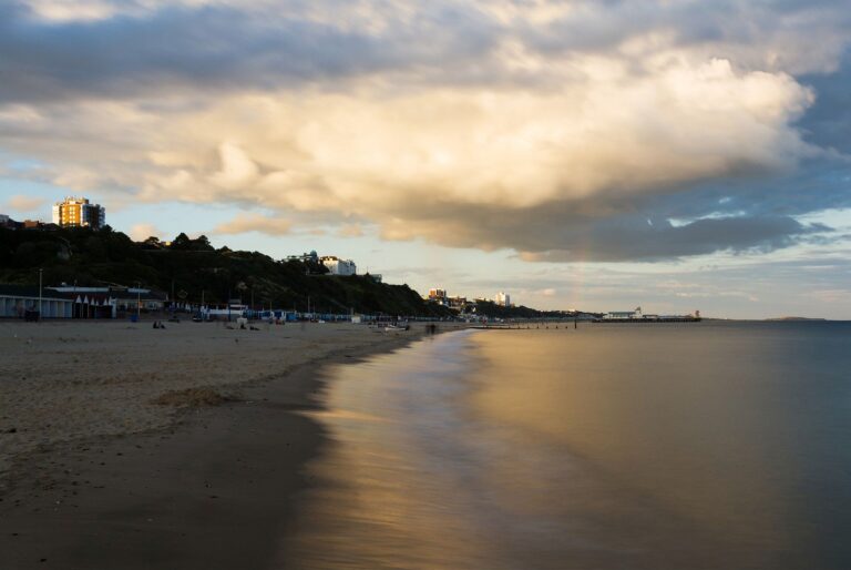 Bournemouth Pier and seafront as a storm cloud drifts over as is illuminated by the sunset. Highcliffe can also be seen on the far right.