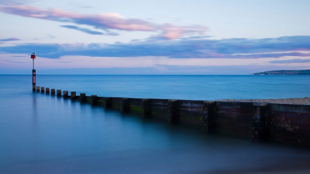 Bournemouth groyne, beach and seafront at sunset. old Harry cliffs can also be seen on the far right.