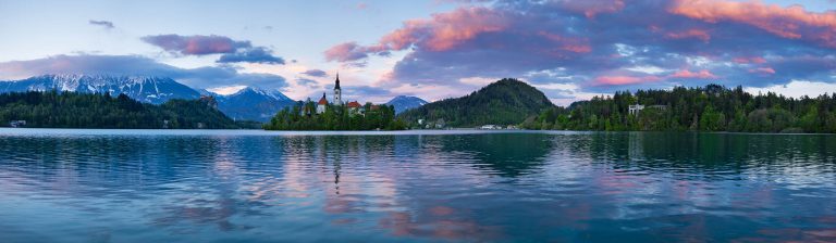 Panoramic view across the beautiful Lake Bled, island church, castle and Karavanke Alps at sunset, Slovenia.