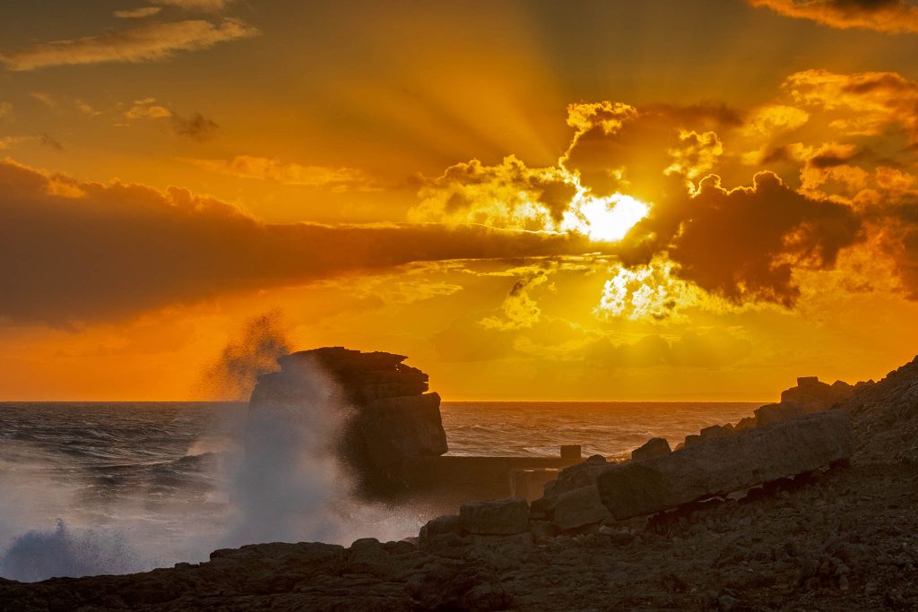 Waves crashing at sunset over Pulpit rock at Portland Bill, near Weymouth, Jurassic Coast, Dorset, England.