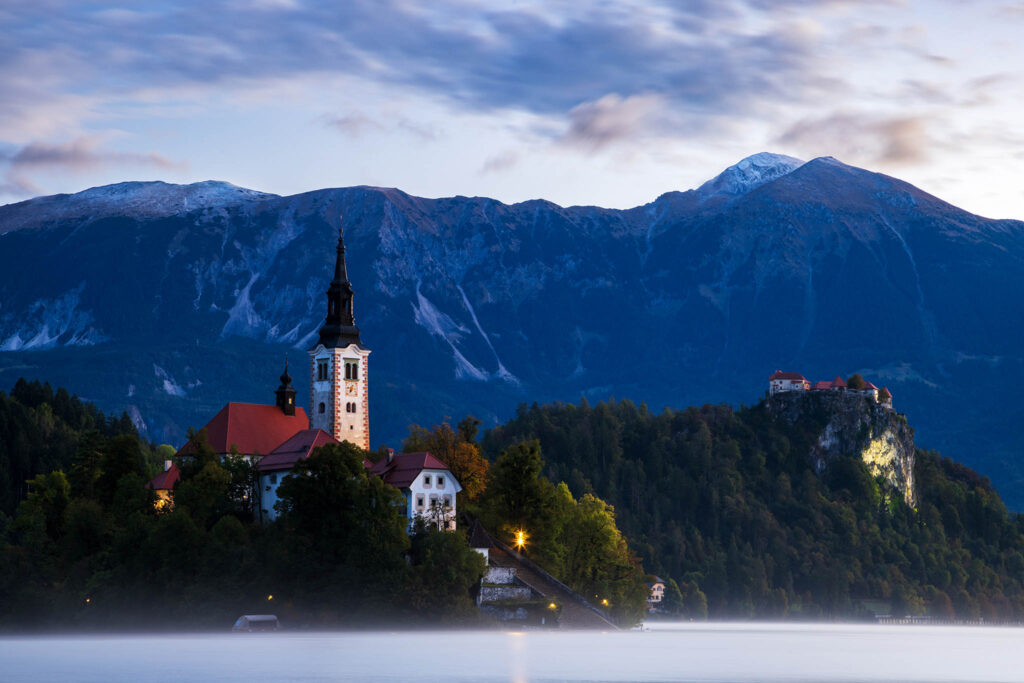 Morning light at Lake Bled's island church and castle with the Karavanke Mountains behind, Slovenia.