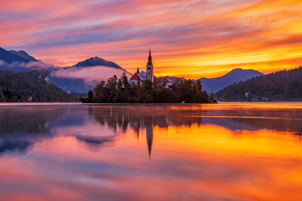 Sunrise over Lake Bled and the island church of the assumption of Mary with the Karavanke mountains in the background, Slovenia.