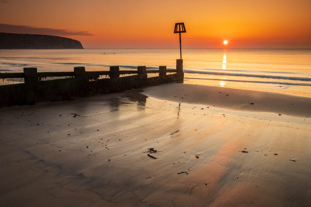 Sun rising Swanage Beach and Groyne, Dorset, England.