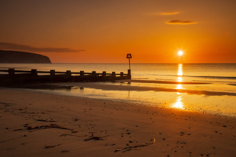 Sun rising Swanage Beach and Groyne, Dorset, England.