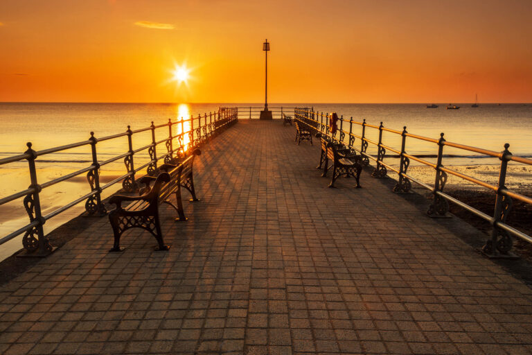 Sun rising behind the old cobbled Banjo Jetty in Swanage, Dorset, England.